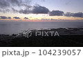 Aerial Panning Shot Of Sea Near Silhouette Hills Against Cloudy Sky At Sunset 104239057