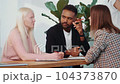 Three serious multiethnic young colleagues at business meeting, btainstorming and discussing project at light office 104373870