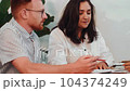 Close-up of two diverse female and male colleagues talking and working together on paperwork 104374249