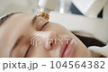 A professional cosmetologist makes facial procedures in a beauty salon with woman patient. Modern technic. LPG skin massage in a professional beauty studio. Beautician makes ultrasound facial massage. 104564382