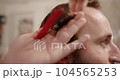 Getting the services of a hairdresser, stylist. Modern haircut in barber shop. Customer Service. Stylish man sitting in barber shop, Hairstylist Hairdresser Male cutting hair with scissors, close-up. 104565253