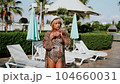 Portrait of happy mature adult woman near the pool. Beautiful smiling caucasian senior woman in hat drink lemonade cocktail enjoying summer vacation 104660031