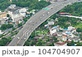 Vehicles drive along the expressway surrounded by the city's lush greenery 104704907