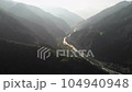 Aerial footage of a river flowing through a steep valley shining in the morning sun 104940948