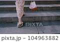 Geta and drawstring bag at the feet of a woman who climbs the stone stairs of a temple in a yukata 104963882
