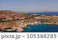 Aerial top view of Greek island, resort on rocky seashore, ship in bay with clear turquoise water, tourists swim and sunbathe on beach, coastal city on horizon, sunny summer day 105388285