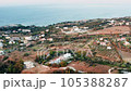 Aerial view sunrise over beautiful village on Greek island, hilly area, early morning rural scene drone flies above coastal town lit with soft sunlight. Blue sea water on background 105388287