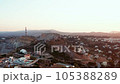 Aerial view sunrise over village on Greek island, hilly area geological formations, early morning or evening golden hour, rural scene drone flies above coastal town lit with warm sunlight 105388289