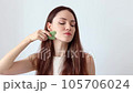 Close-up portrait of a beautiful girl, red-haired woman massaging her face with a stone scraper 105706024