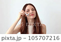 A beautiful woman gives a facial massage with a silver facial massager to relieve facial swelling 105707216