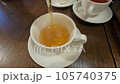 Tea is poured into a white cup and saucer.  105740375