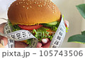 A woman holds a hamburger in her hands in the home kitchen. 105743506