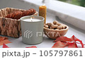Still life candle flame, peanut, fallen leaves, wicker basket, bagel on a table, home decor in a cozy house. Autumn weekend concept. 105797861