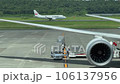 Operators unload an airplane, with an airplane taking off in the background 106137956