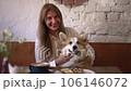 FullHD Woman strokes pet dog and sits in cafe spbd. Young beautiful female owner touching cute corgi and looking with happy smile, sitting at table with coffee in cafeteria. One millennial person 106146072