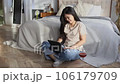 Happy beautiful woman in casual clothes working on digital tablet sitting near bed 106179709