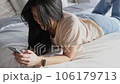 Beautiful asian woman in casual clothes using smartphone lying on the bed 106179713