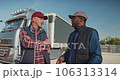 Automobile industry. Conversation between two truck multicultural drivers. Colleagues lorry drivers talking in parking lot after work. Workers at workplace. Professional transportation concept. 106313314