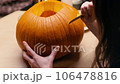 Preparing pumpkin for Halloween. Woman sitting and carving with knife face details of halloween Jack O Lantern pumpkin at home for her family. 106478816