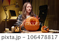 Preparing pumpkin for Halloween. Woman sitting and cleaning carved halloween Jack O Lantern pumpkin at home for her family. 106478817