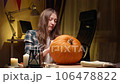Preparing pumpkin for Halloween. Woman sitting and marking pumpkin with pencil before carving halloween Jack O Lantern at home for her family. 106478822