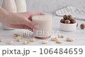 Cashew milk. taking a glass with vegan milk made of cashew nuts, hand grabbing a glass from white table, non-dairy drink, 4k horizontal video 106484659