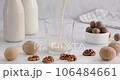 Vegan milk, pouring alternative milk made of walnuts into a glass on white wooden table, non-dairy product, kitchen table on background, 4k video 106484661