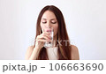 A beautiful young woman drinks pills, vitamins, and badas and washes them down with a glass of water 106663690