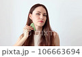 Close-up portrait of a beautiful girl, red-haired woman massaging her face with a stone scraper 106663694