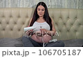 A pregnant woman in a homey setting applies gel to a device used for listening to the baby's heartbeat 106705187