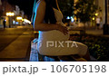 A pregnant woman sits on a bench in a public place late in the evening, gently caressing her belly. 106705198