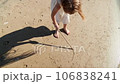 Girl child drawing with a stick on the sand on the beach and having fun 106838241