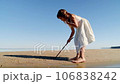 Girl child drawing with a stick on the sand on the beach and having fun 106838242