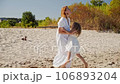 Mom spinning with her daughter and have fan on the sandy beach 106893204