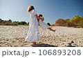 Mom spinning with her daughter and laughing on the sandy beach 106893208