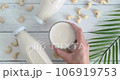 Hand taking a glass with cashew milk from table, vegan drink served on table, alternative milk, slow motion video, closeup video 106919753