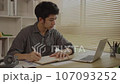 Studying online using a laptop, Man watching live video or video call of teacher teaching on laptop in her home, Take notes of important conversations and messages during the teacher's teaching.  107093252