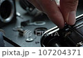 Close-up of hands screwing a screw into an old camera. 107204371