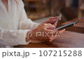 An old woman uses a credit card to shop on a smartphone. Senior female makes a purchase in an online store. Order online, enter the card number. 107215288