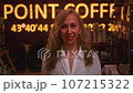 Portrait: a beautiful aged woman looks at the camera in a cafe. Senior female smiles in a restaurant or coffee shop.  107215322