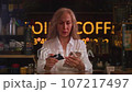 An old woman uses a credit card to shop on a smartphone. Senior female makes a purchase in an online store. Order online, enter the card number. 107217497