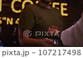 An old woman pays for purchases with a smart watch contactless, NFC technology. Senior female puts her hand to the pos terminal in cafe or restaurant 107217498