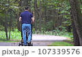 A man with a child in a stroller walks in a forest park 107339576