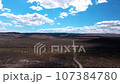 Train hauling wagons through the desert steppe under a brilliant blue sky. 107384780