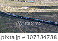 Train hauling wagons through the desert steppe under a brilliant blue sky. 107384788