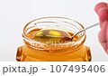 Dripping honey from spoon close up 107495406