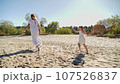 Mom and daughter in white dresses running on the beach and laughing 107526837