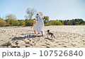 Mom and daughter in white dresses running on the beach and laughing 107526840