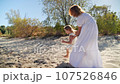 Mom spinning with her daughter and laughing on the sandy beach 107526846