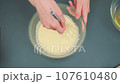 Stirring eggs with a kitchen whisk 107610480